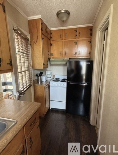 A kitchen with wooden cabinets and a black fridge.
