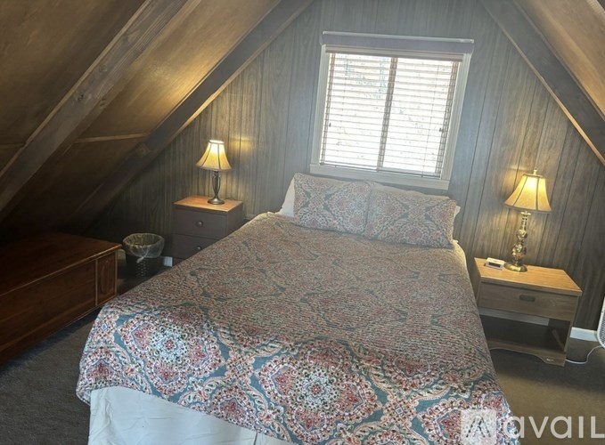 A bedroom with a bed, nightstands, and lamps.