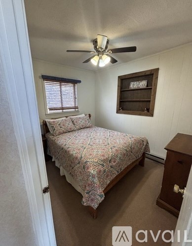 A bedroom with a bed, dresser, and a window with blinds.