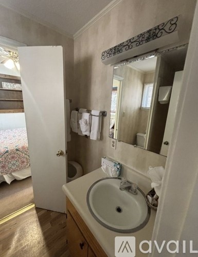 A bathroom with a sink, mirror, and towel rack.