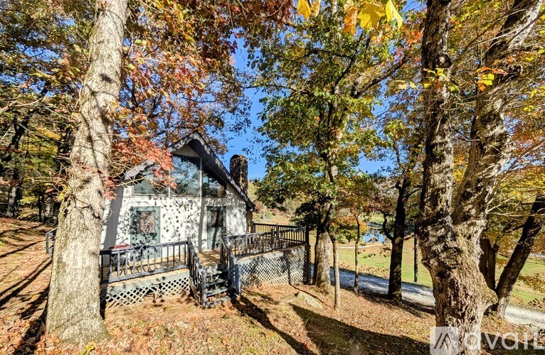 A small house surrounded by trees with autumn leaves.