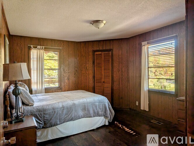 A bedroom with a bed, nightstand, and window.