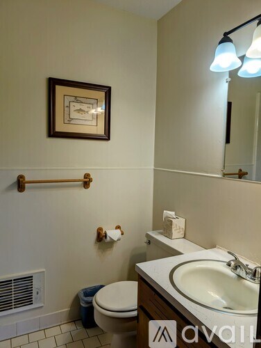 A bathroom with a toilet, sink, and a picture on the wall.