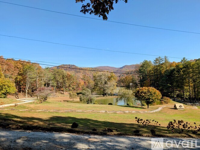 A beautiful landscape with a lake, trees, and a small hut.