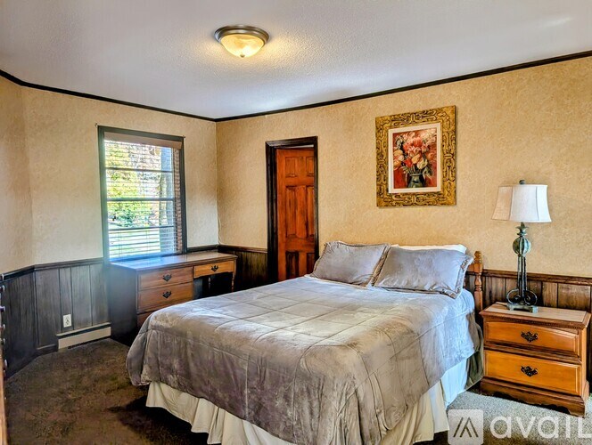A bedroom with a bed, dresser, and window.