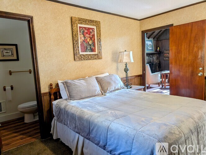 A bedroom with a bed, a chair, and a painting on the wall.