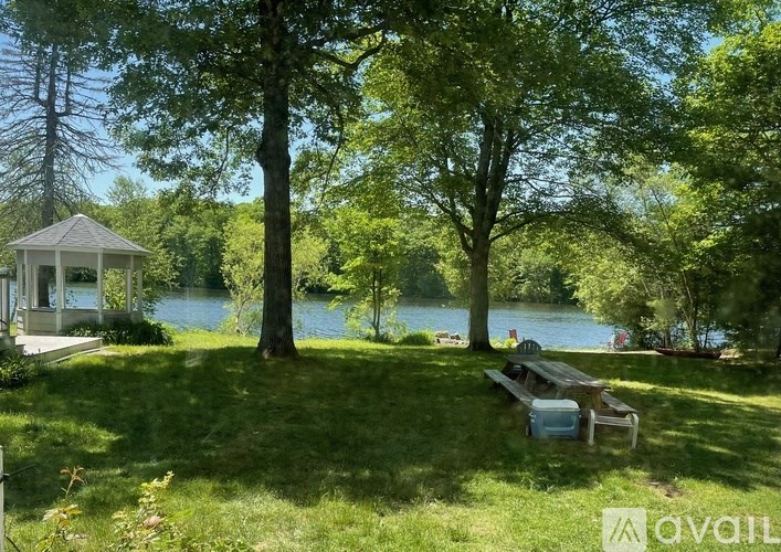 A gazebo sits on a lawn by a lake.