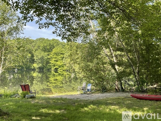 A serene lakeside setting with chairs and a canoe.