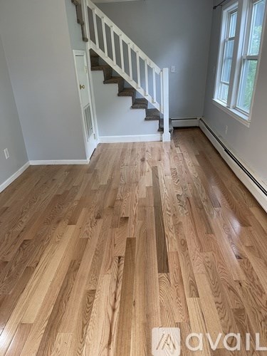 A room with wooden flooring and a staircase.