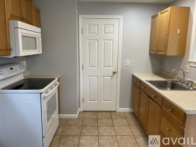 A kitchen with white appliances and wooden cabinets.