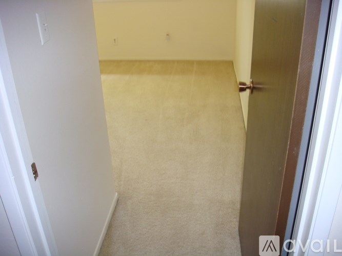 A room with a carpeted floor and a door on the right side.