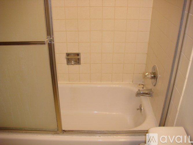 A white bathtub with a silver faucet and a silver shower door.