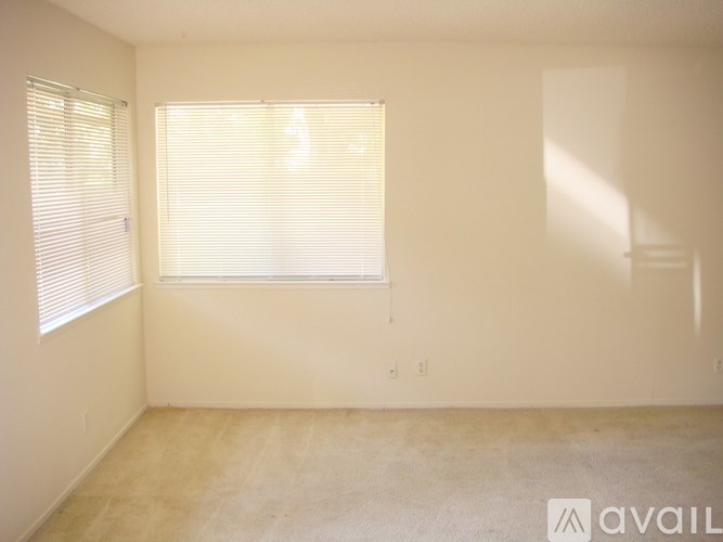 A room with a window covered by blinds and a wall with a switch.