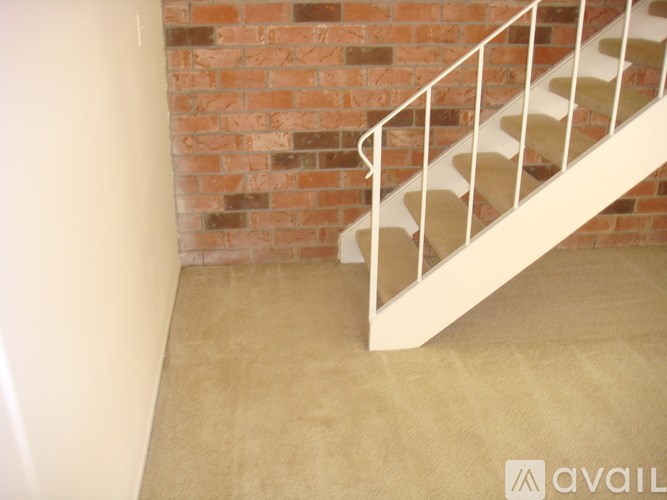 A staircase with a metal railing and a brick wall.