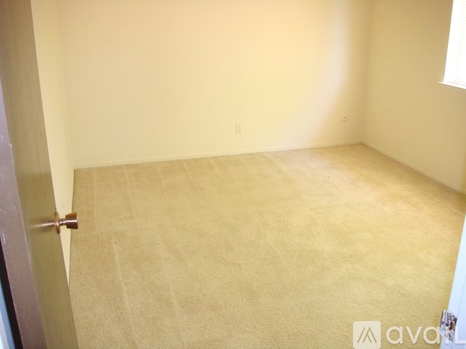 A room with a carpeted floor and a door on the left side.