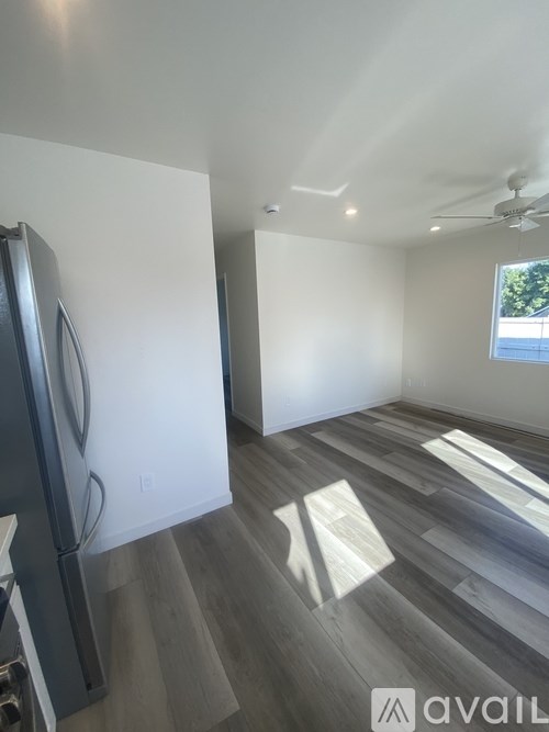 A kitchen with a refrigerator and wooden flooring.