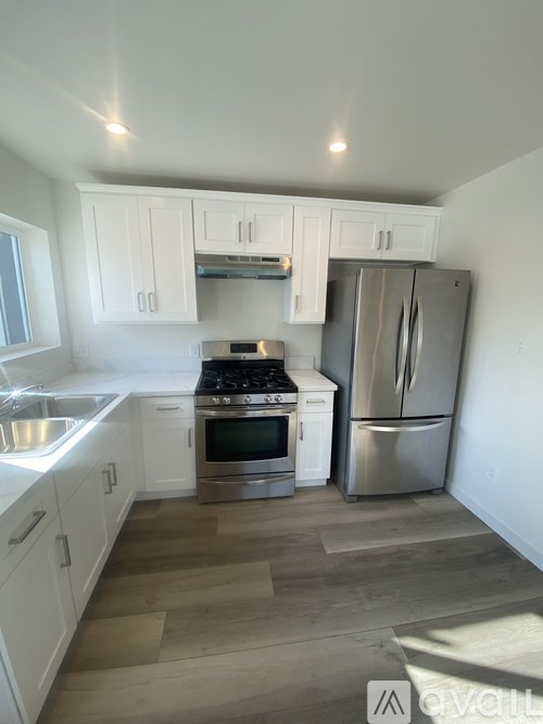 A kitchen with white cabinets and a stainless steel refrigerator.