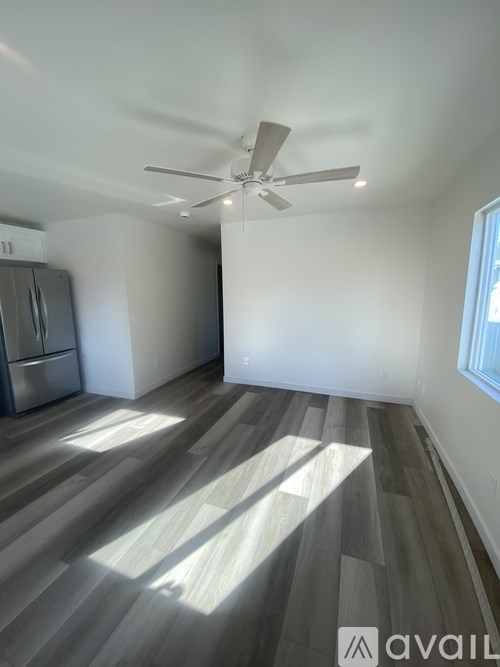A room with a ceiling fan and wooden flooring.
