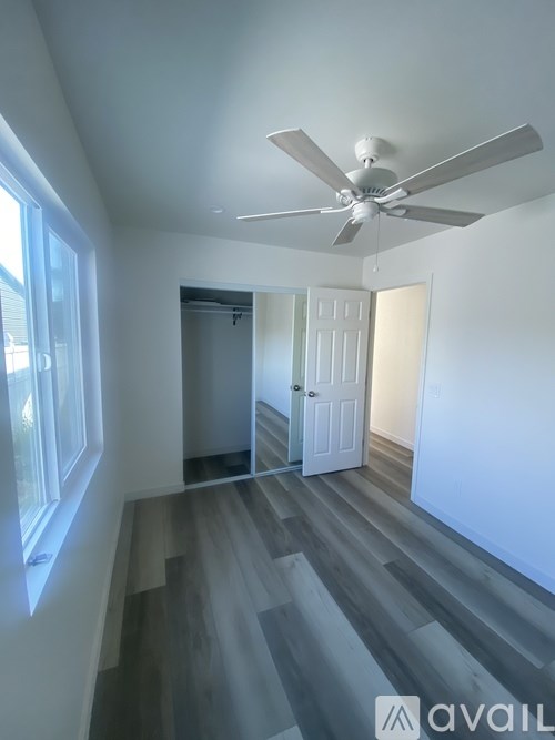 A room with a ceiling fan and wooden flooring.