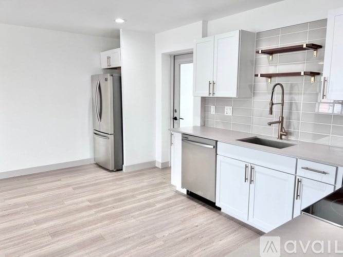 A kitchen with white cabinets and a stainless steel refrigerator.