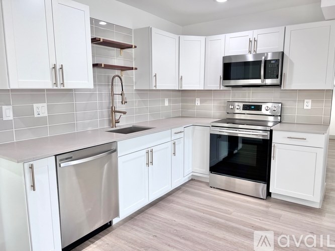 A modern kitchen with white cabinets and stainless steel appliances.