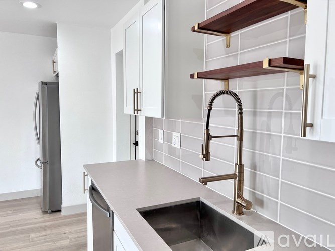 A kitchen with a sink, faucet, and a refrigerator.