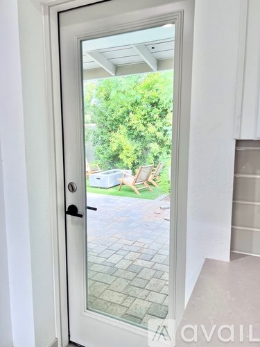 A white door with a glass window leading to a backyard.