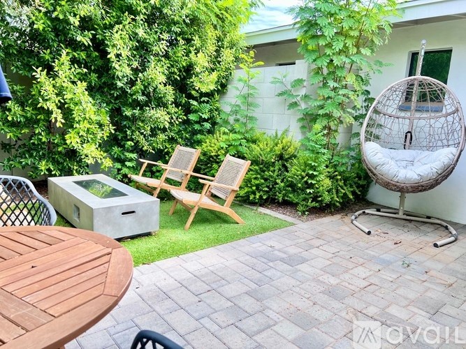 A patio with a table, chairs, and a hanging chair.