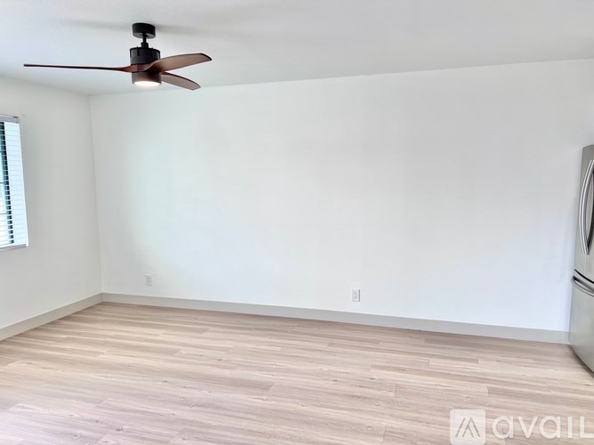 A room with a ceiling fan and wooden flooring.