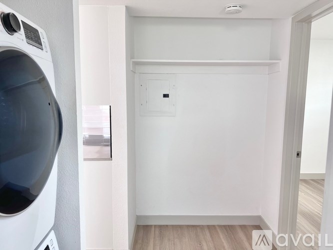 A small white room with a washing machine on the left and a shelf on the right.