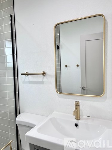 A bathroom with a white sink and a gold framed mirror.