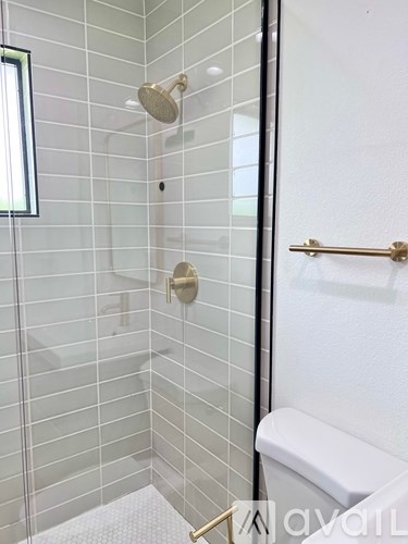 A white toilet is in a bathroom with a glass shower stall.