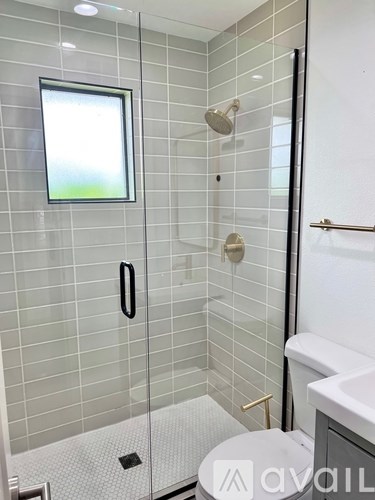 A bathroom with a glass shower stall and a toilet.