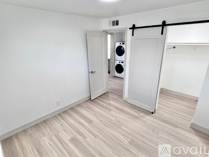 A room with a white door and a wooden floor.