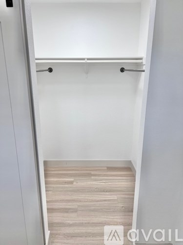 A white closet with a shelf and a wooden floor.