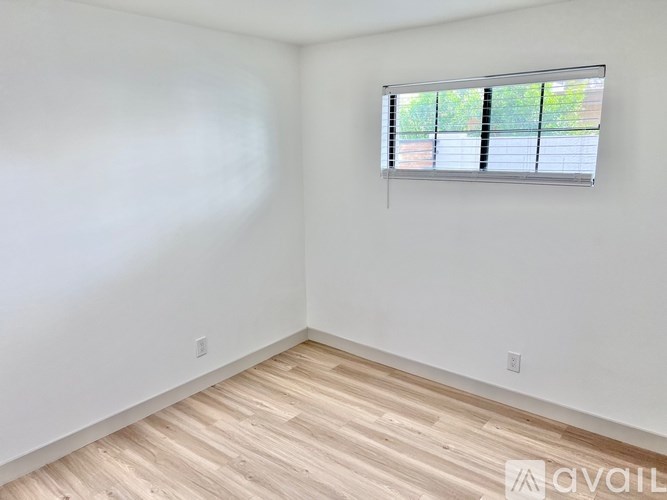 A room with a window and wooden flooring.