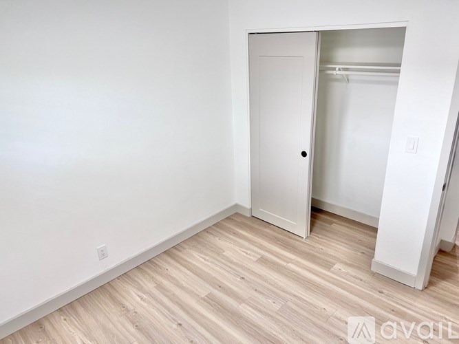 A room with a white door and wooden flooring.