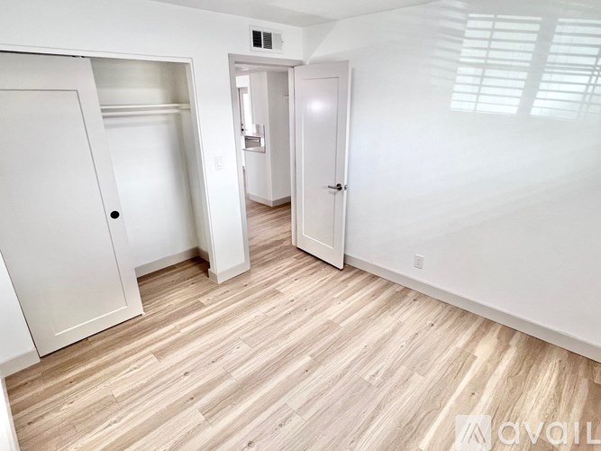 A room with white walls and wooden flooring with two doors.