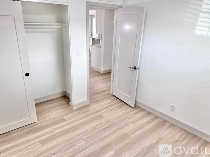 A room with white walls and a wooden floor with two doors.