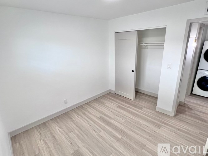 A room with a white door and a washing machine in the background.