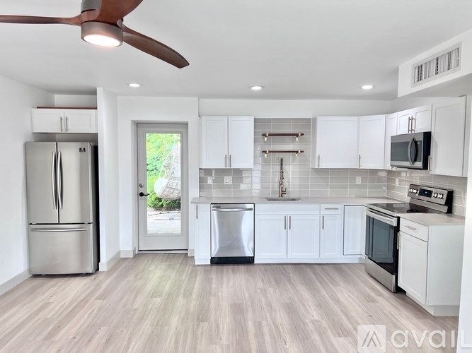 A modern kitchen with white cabinets and stainless steel appliances.