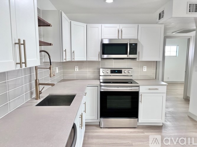 A modern kitchen with white cabinets and stainless steel appliances.