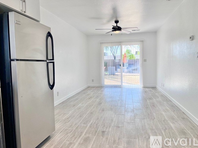 A room with a ceiling fan and a refrigerator.