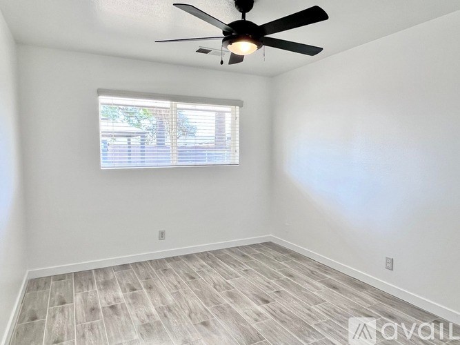 A room with a ceiling fan and a window with blinds.