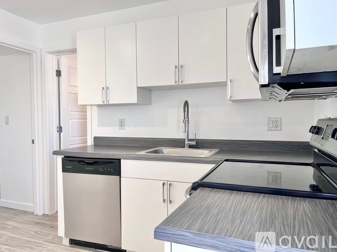 A kitchen with white cabinets and a black countertop.