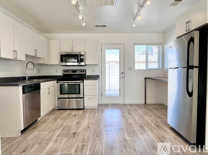 A kitchen with white cabinets and a black countertop.