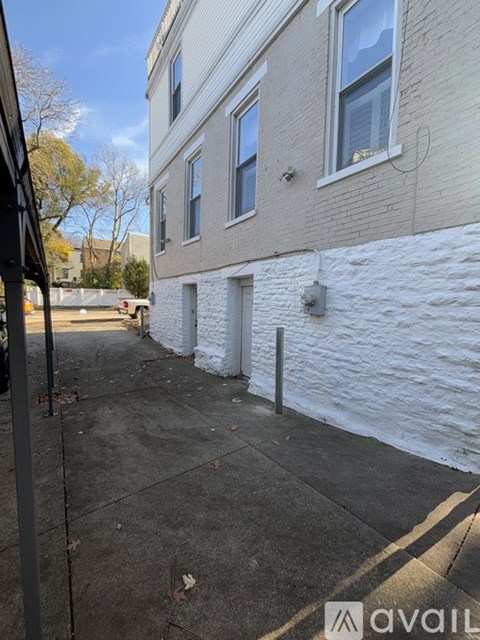 A white brick wall separates a sidewalk from a building.