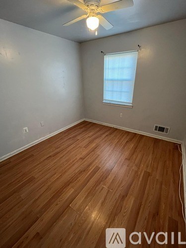 A room with wooden flooring and a ceiling fan.