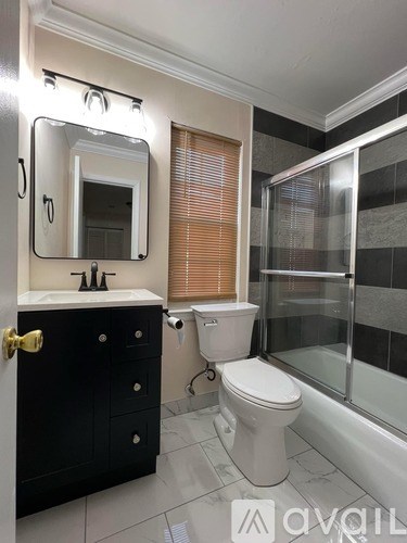 A bathroom with a toilet, sink, mirror, and shower.