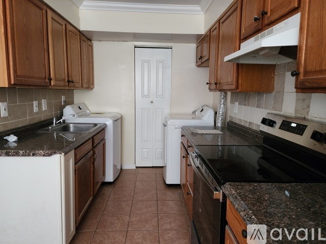 A kitchen with white appliances and brown cabinets.